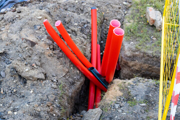 several red plastic conduit pipes in ditch