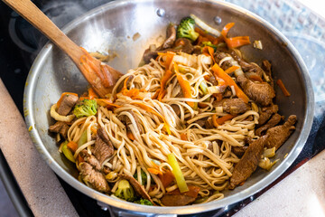 stirring of frying meat, noodles and vegetables