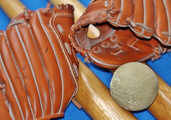 Guantes de béisbol, bates y pelota sobre fondo azul