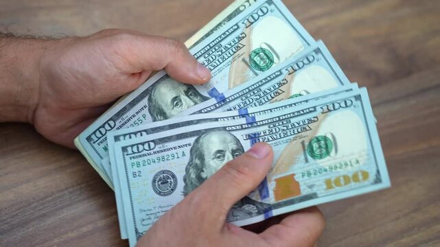 Startup founder holds pack of dollar banknotes carefully counting capital raised from investors crucial for next phase of company expansion and development