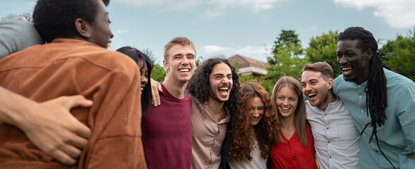 Diverse happy friends laughing together outdoors sharing authentic multicultural joy in genuine...