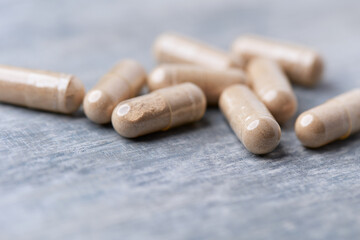 Reishi capsules. Concept for a healthy dietary supplementation. Wooden background. Soft focus. Close up.	