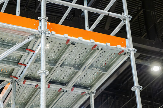 Fragment mezzanine inside building. Steel scaffolding made of metal parts. Mezzanine in industrial building. Warehouse hangar with scaffolding for placing shelving. Metal mezzanine with orange frames