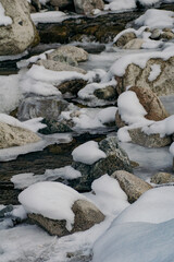 clear water in the mountain river with snow, ice, stones in the winter season