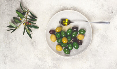 a mix of olives, a variety of Chalkidiki, verdi giganti and Kalamata, on a plate with a spoonful of olive oil, top view, no people,