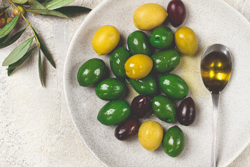 a mix of olives, a variety of Chalkidiki, verdi giganti and Kalamata, on a plate with a spoonful of olive oil, top view, no people,