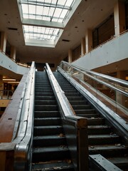 An abandoned escalator in a deserted shopping mall, showing neglect.