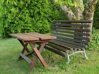A garden bench with a homemade table under an old walnut tree