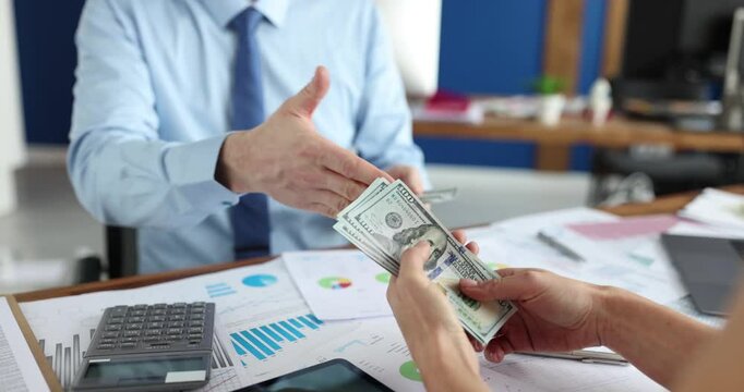 Gentleman in shirt and tie counts dollar bills before handing to companion slow motion. Businessmen make financial deal by shaking hands over table