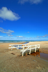 Ocean beach, wood bridge and blue sky for travel, holiday destination and location for summer vacation. Sea water, sand and land for tourism, adventure and waves in horizon on tropical island in Bali