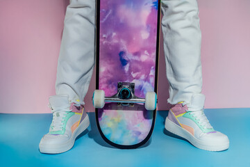 Female legs in white jeans and retro style high-top multicolor sport sneakers shoes standing with...