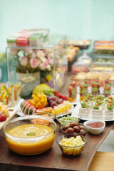 Assorted fresh fruit desserts displayed on wooden table with arrangement of fruit skewers, dips,...