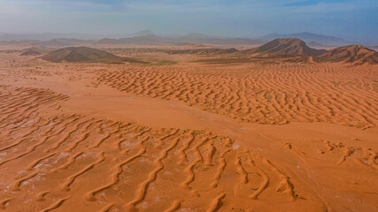 Moroccan Sahara Desert, ancient black volcanic mountains, the Sahara River Oued Ghris, stunning Acacia trees, wild camels, and desert camp,  landscape where golden sand dunes merge with green plants