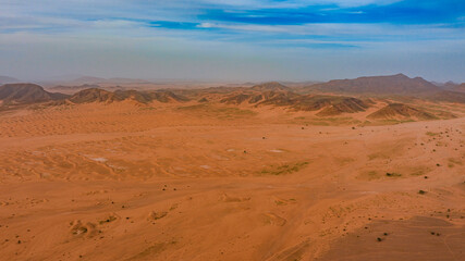 Moroccan Sahara Desert, ancient black volcanic mountains, the Sahara River Oued Ghris, stunning Acacia trees, wild camels, and desert camp,  landscape where golden sand dunes merge with green plants