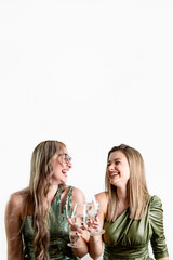 Two beautiful young blonde women in green dresses celebrating the new year, toasting with champagne