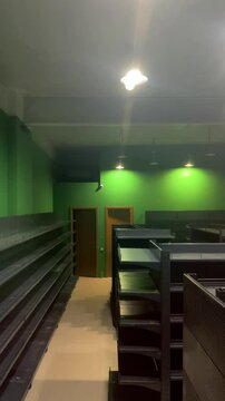 Vertical 4K defocused video. Showcase of an empty closed store. Empty gray shelves in shop, green wall, bright light, lamp. Concept of 11 november, Black Friday, cyber monday offer, online shopping