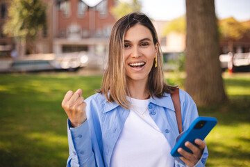 Blonde short hair woman browsing internet with cellphone mobile phone wearing casual clothes shirt...