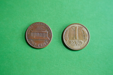 One-cent coin and a similar coin resembling one cent, Russian ruble, on a green background,...