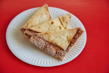 Freshly baked tortilla chips with sugar and cinnamon on a red background, close-up, limiting sweet and pastry consumption, sweet cookies on a plate.