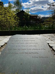 William Wordsworth's poetry etched on a slate, surrounded by greenery and a rustic building, celebrating nature and literary heritage. Orientation portrait.