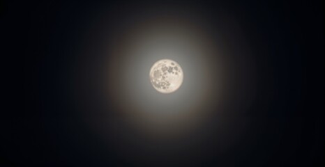 Bright full moon surrounded by a halo in a dark sky representing celestial phenomenon
