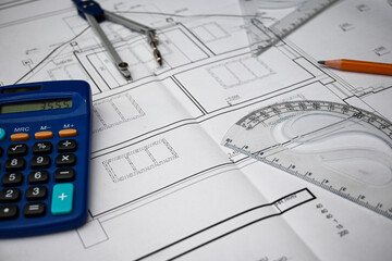 Workplace of architect designing blueprint of building using calculator, compass, protractor, ruler...