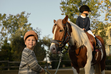 Obraz premium Young boy guiding a horse in a traditional stable, embracing the timeless connection between humans and animals.
