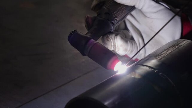 Close-up of a skilled welder performing TIG welding on a metal pipe, with a bright torch arc illuminating the joint. The video highlights the precision and craftsmanship in this intricate welding 