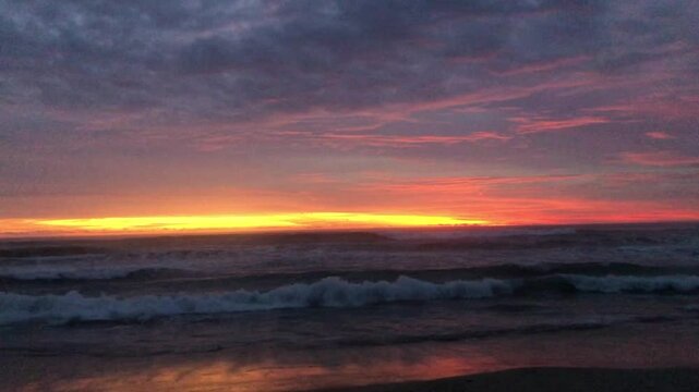 The sun sets over a calm beach, gentle waves wash over the shore. Golden times are on the horizon.