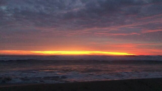 The sun sets over a calm beach, gentle waves wash over the shore. Golden times are on the horizon.