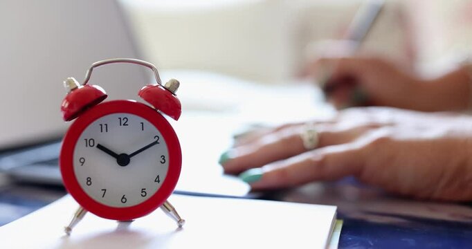 Businesswoman works near vintage alarm clock placed on table. Woman employee manages time effectively to meet professional goals within timeframe