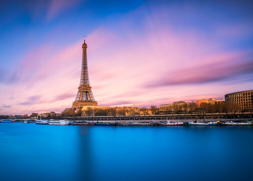 Boats moored on River Seine with the Eiffel Tower and city skyline at sunset, Paris, France