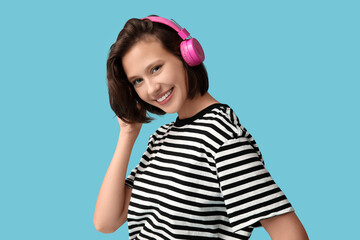 Happy young woman in modern headphones on blue background