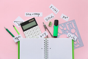 Notebook with calculator and school stationery on pink background