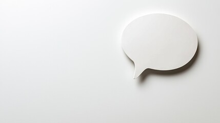  a white speech bubble on a white wall The speech bubble is made of paper and has a glossy finish It is the focal point of the image, standing out against the plai