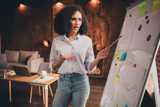 Young businesswoman presenting data on whiteboard in stylish modern office setting during sunny day