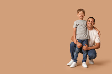 Happy father hugging his little son on beige background