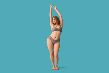 Beautiful young happy body positive woman in stylish underwear on blue background