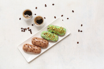 Plate with sweet eclairs and coffee on light  background