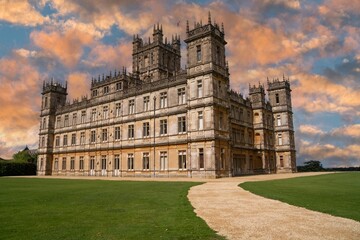 Majestic Highclere Castle in England with a beautiful sunset sky and light rays.
