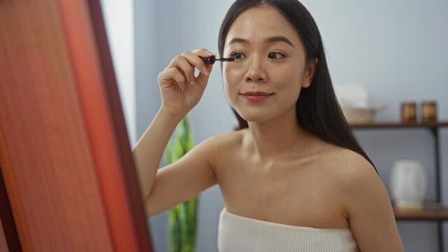 Woman applying makeup in front of a mirror in a serene spa room creating a calm and relaxing beauty routine environment
