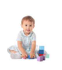 Cute baby girl playing with cubes on white background