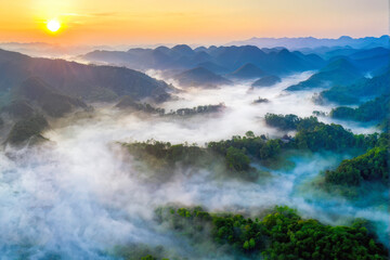 Fototapeta premium A breathtaking aerial view of mist-covered mountains at sunrise, with golden light illuminating the serene landscape. Generative AI