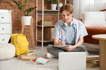 Male student in eyeglasses with notebook studying online at home