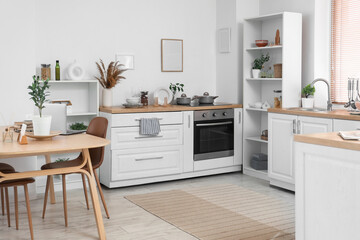 Interior of light kitchen with dining table, counters and plants