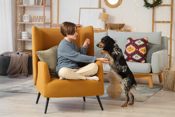 Little boy with cute cocker spaniel sitting in armchair at home