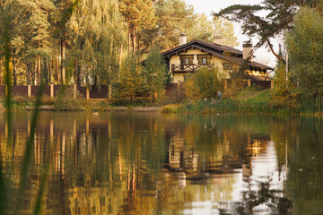 A tranquil lakeside retreat surrounded by vibrant autumn foliage reflects beautifully on the calm water.