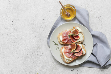 Plate of delicious fig bruschetta with prosciutto and ricotta cheese on white background