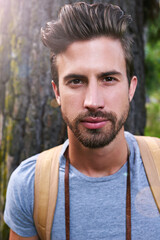 Fototapeta premium Man, portrait and hiking in forest for fitness, explore outdoor and woods for adventure on vacation. Male person, trekking and backpacking in nature for freedom, active guy and travel hobby in park