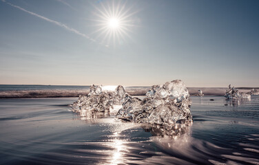 Long exposure image of broken off glacier ice washed up on shore of black sand Diamond Beach on Iceland